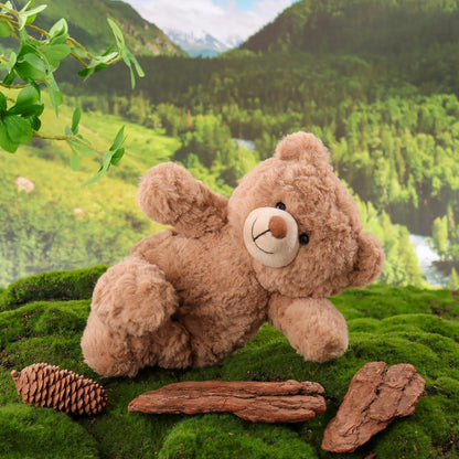 Teddy bear on a mossy rock with a scenic background of trees and mountains.