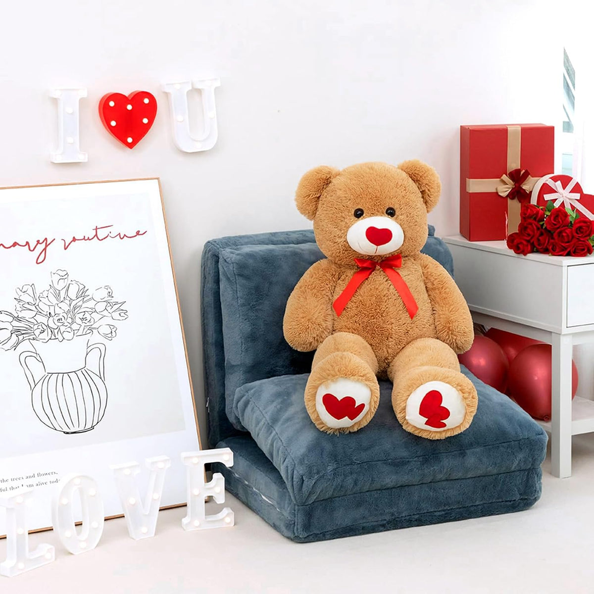 Teddy bear with heart details sitting on a blue cushion in a room with decorative elements.