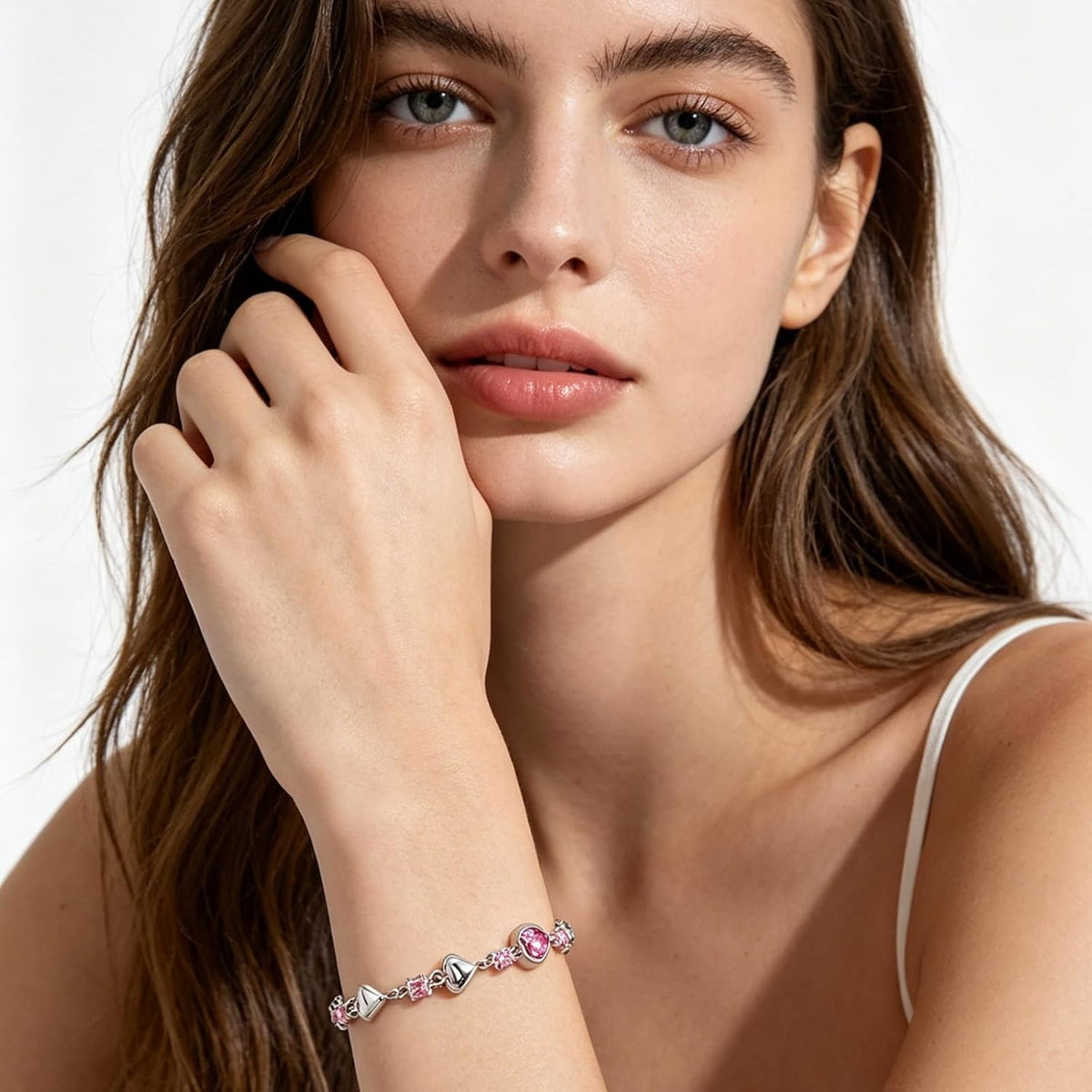 A close-up lifestyle shot of a model wearing a delicate silver-toned bracelet adorned with small, colorful round beads in pink, green, and blue, set against a clean white background.