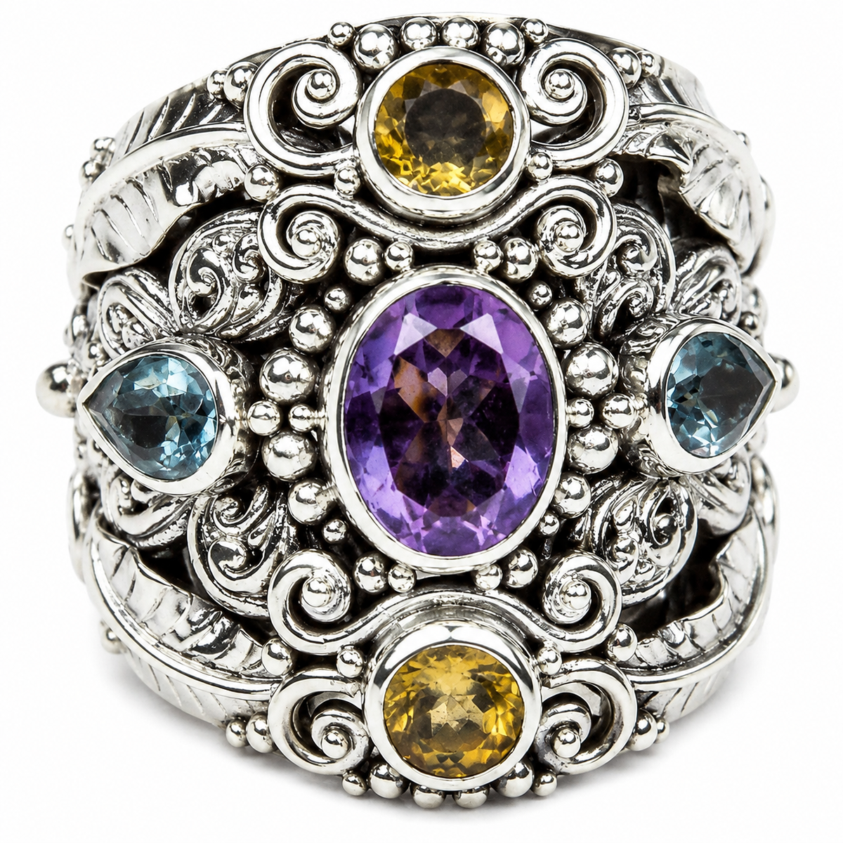 An ornate sterling silver ring featuring a large oval purple amethyst center stone, flanked by two marquise-cut light blue sapphires and two oval yellow citrines, set against a white background.
