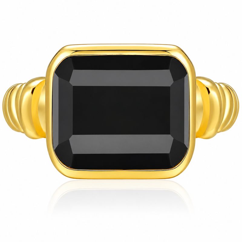 A gold ring featuring a large, faceted rectangular black gemstone in a bezel setting, with a ribbed gold band on a clean white background.